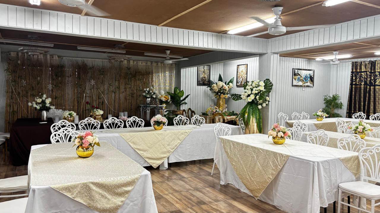 Wide view of banquet hall with white tables and floral centerpieces