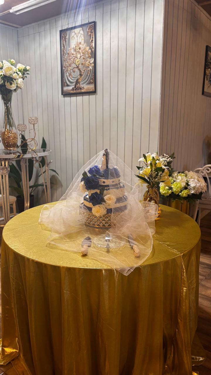 Wedding cake on gold tablecloth with blue floral accents