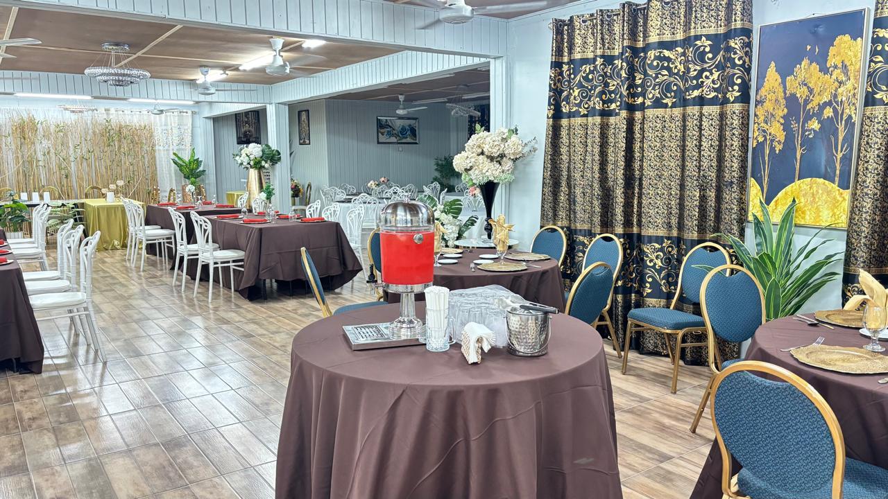 Wide view of the dining hall with brown-linen tables and gold curtains